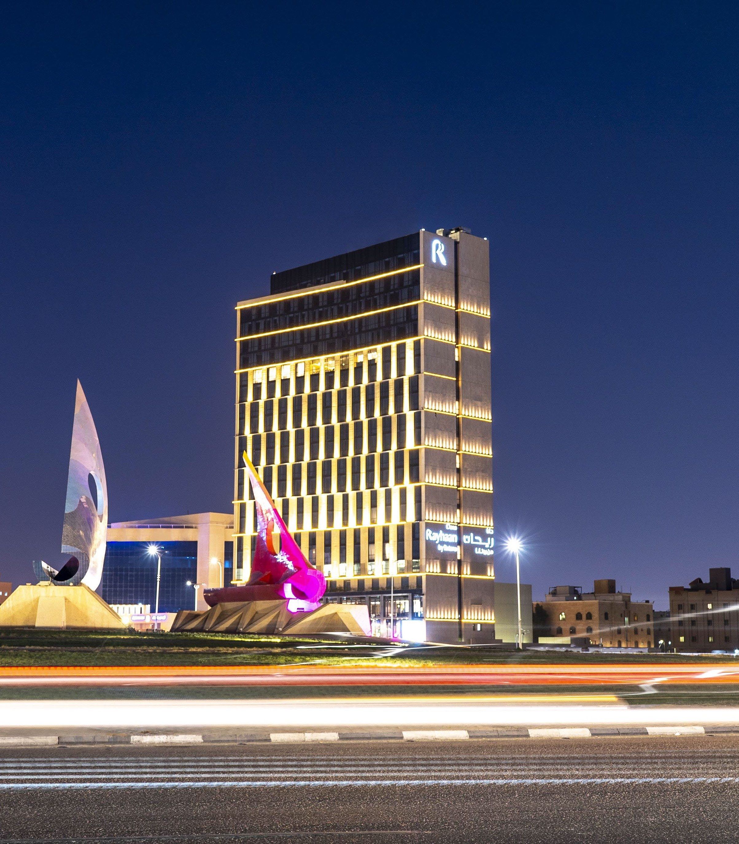 The hotel tower at night beyond the Al Khobar sculptures